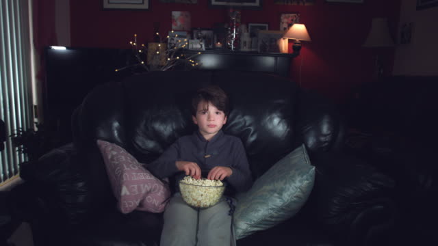4-k-tiro-auténtico-de-un-divertido-niño-viendo-películas-y-comiendo-palomitas-de-maíz