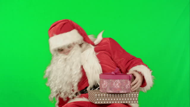Santa-Claus-sosteniendo-un-regalo-en-su-mano-en-una-pantalla-verde-Chrome-Key