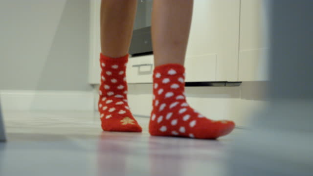 Female-legs-with-red-christmas-socks-walking-in-the-kitchen.