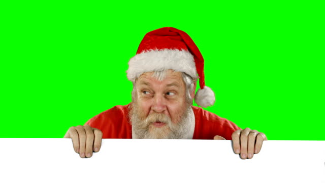 Surprised-santa-claus-hiding-behind-green-screen