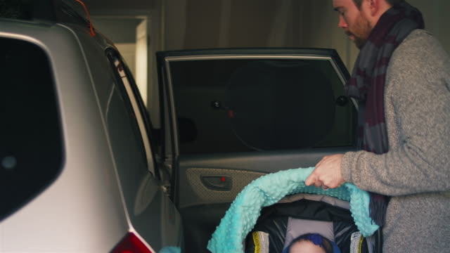 Vater-nimmt-seinen-schlafenden-Tochter-aus-dem-Auto-in-ihrem-Autositz