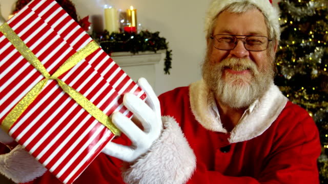 Porträt-des-Weihnachtsmannes-halten-Geschenkbox-mit-Finger-auf-die-Lippen
