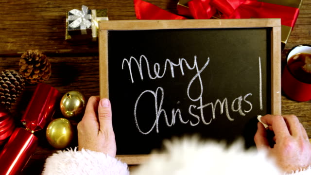 Santa-claus-writing-merry-christmas-on-slate
