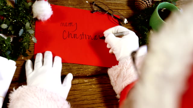 Santa-claus-writing-merry-christmas-on-card