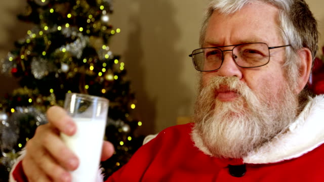 Santa-Claus-entspannend-auf-Stuhl-süßes-Essen-und-trinken-Milch