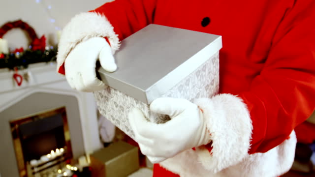 Mid-section-of-santa-claus-holding-gift-box