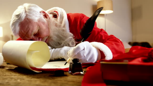 Papá-Noel-durmiendo-en-el-escritorio-mientras-escribía-una-carta-con-una-pluma