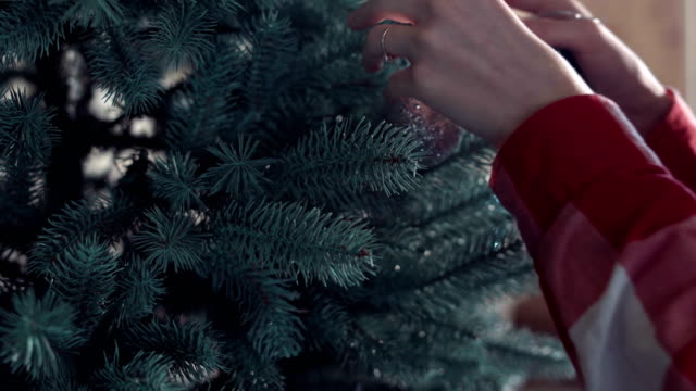 Mujer-poniendo-pelotas-en-el-árbol-de-Navidad