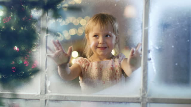 Am-Weihnachtsabend-sieht-niedliche-kleine-Mädchen-durch-das-Fenster-und-lächelt.