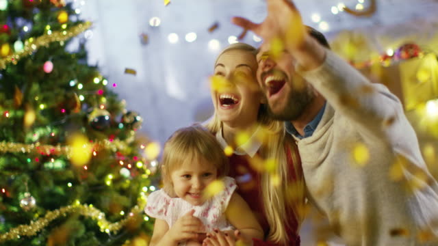 Am-Heiligabend-haben-Vater,-Mutter-und-ihre-kleine-Tochter-gute-Zeit-gefeiert-mit-Shooting-Confetti.