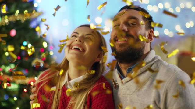 On-Christmas-Eve-Handsome-man-and-Beautiful-Woman-Have-Good-Time-Celebrating-with-Shooting-Confetti.