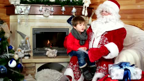 boy-sitting-on-santa's-lap,-child-giving-saint-nicolas-his-cristmas-wishlist-in-envelope,-holiday