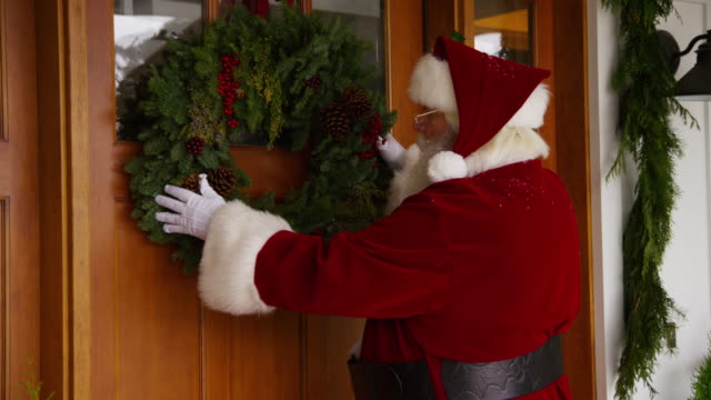 Santa-Claus-putting-wreath-on-door