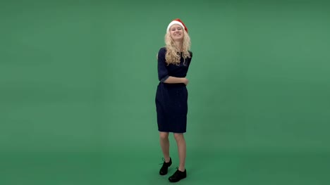 Young-blonde-woman-in-a-santa's-cap-dancing-and-hanging-out,-chroma-key-green-screen