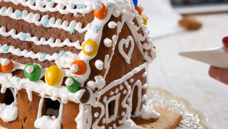 Female-decorates-a-gingerbread-house-with-a-cream-inside-the-piping-bag