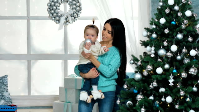 Mutter-mit-ihren-10-Monate-alten-Baby-Girl-dekorieren-Weihnachtsbaum-im-Wohnzimmer