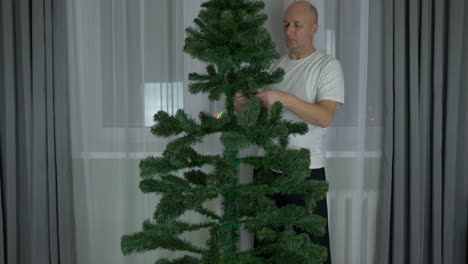 Timelapse-fast-motion-effect-sequence.-Shaping-pine-evergreen-fir-tree-for-Christmas.-Adult-caucasian-man-at-home-preparing-fir-pine-tree-for-decorating-for-Christmas-time.