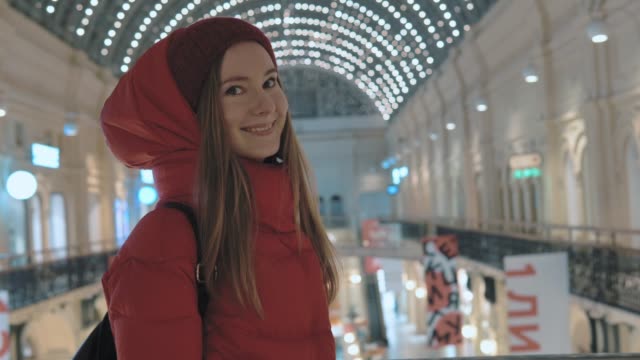 hermosa-mujer-joven-con-una-amplia-sonrisa-se-encuentra-caminando-por-la-Alameda-de-compras-grande-en-Moscú