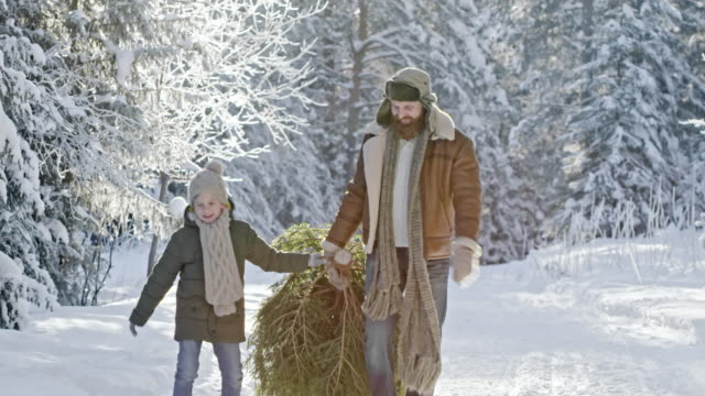 Hombre-y-muchacho-llevando-árbol-de-Navidad-del-bosque
