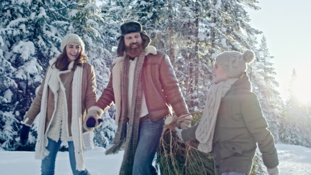 Familia-llevando-árbol-de-Navidad-del-hogar-del-bosque
