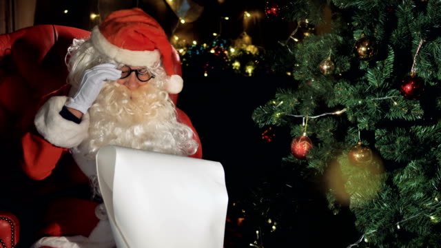Santa-Close-up-cerca-decorado-árbol-de-Navidad-leyendo-lista-de-Navidad-desea.
