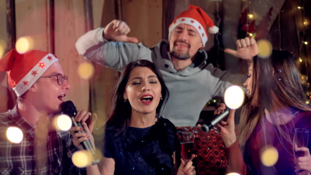 Group-of-joyfull-friends-singing-karaoke-having-fun-at-Christmas-party.-4K.