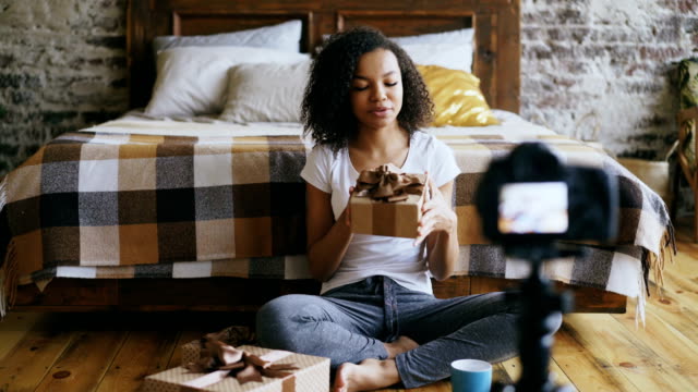 Fröhliche-afroamerikanische-Mädchen-Aufnahme-video-Blog-über-Verpackung-Weihnachten-Geschenk-Box-zu-Hause