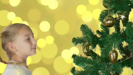 Excited-young-white-girl-decorating-christmas-tree-and-with-happy-looking-to-fir-tree.-Preparing-for-Merry-Christmas-and-Happy-New-Year-celebrate-Holiday.-Abstract-gold-flicker-background.