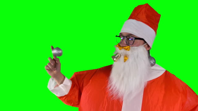 Weihnachtsmann-auf-grünem-Hintergrund-spielt-mit-Weihnachtsschmuck.