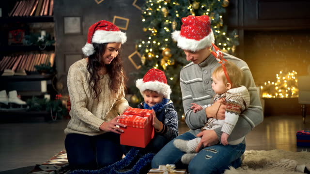 Familia-abrir-regalo-frente-a-árbol-de-Navidad