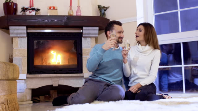 Happy-married-couple-with-champagne-near-fireplace