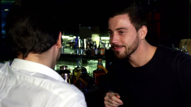 Young-male-friends-talking-while-having-drinks-together-at-the-bar