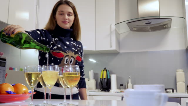 Hübsches-Mädchen-gießt-Champagner-in-Gläser-in-der-Küche-zu-Hause