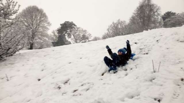 Young-boy-enjoying-a-sledge-ride-on-a-snowy-hill