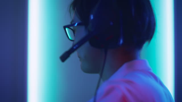 Close-up-Portrait-Shot-of--the-Professional-East-Asian-Gamer-Playing-in-Online-Video-Game-on-His-Personal-Computer.-Talking-into-Microphone.-Room-Lit-by-Neon-Lights-in-Retro-Arcade-Style.-Cyber-Sport-Championship.