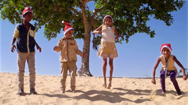 Kinder-mit-Santa-Hüte-springen-in-sand
