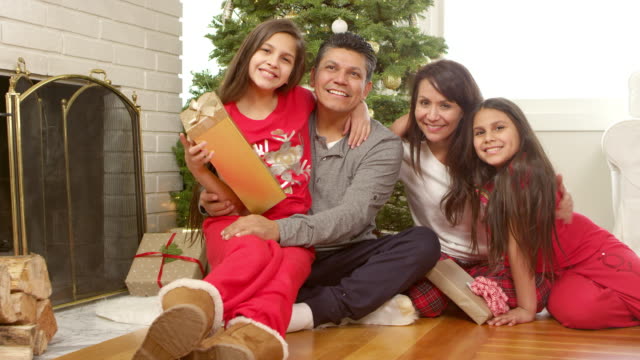 Familia-s\'encuentra-en-la-parte-delantera-de-un-árbol-de-Navidad-con-regalos