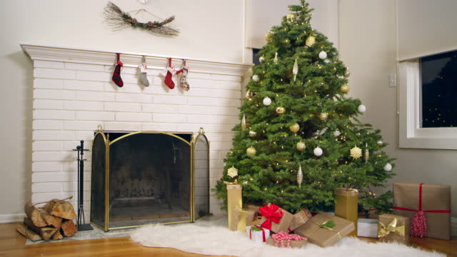 Schwenk-nach-unten-von-einem-Weihnachtsbaum-mit-Geschenken-unter-es-neben-einem-offenen-Kamin