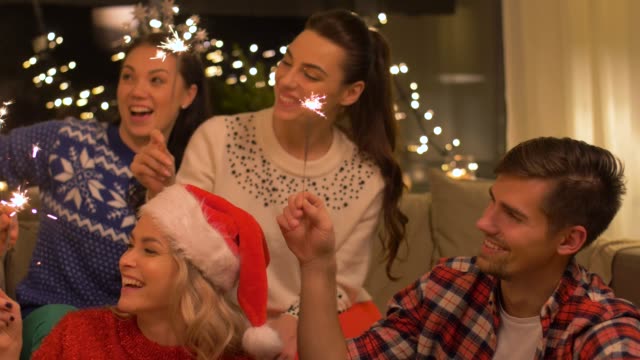 Glückliche-Freunde-mit-Wunderkerzen-feiert-Weihnachten-zu-Hause-feiern