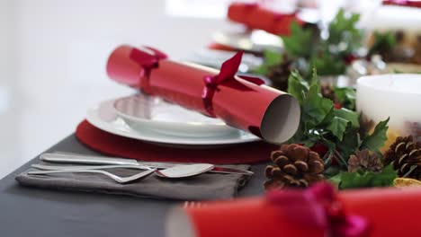 Cierre,-tiro-mano-mostrando-cubiertos-en-una-mesa-de-comedor-de-Navidad-decorada,-con-galletas-de-Navidad-rojo-dispuestos-en-placas-de