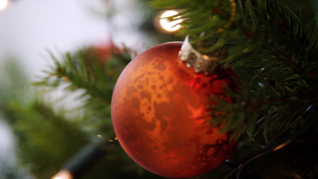 Handheld,-geringe-Schärfentiefe-Nahaufnahme-von-glitzernden-Kugeln-hängen-an-einen-Weihnachtsbaum-mit-Lichterketten