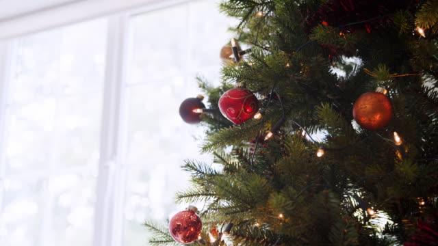 Nach-unten-kippen-Sie-Schuss-vom-oberen-Rand-ein-geschmückter-Weihnachtsbaum-vor-einem-Fenster