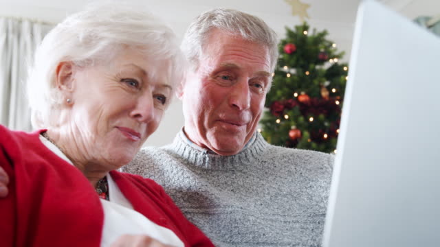 Senior-pareja-llamar-Navidad-Video-a-familia-en-portátil