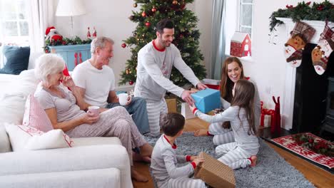 Drei-Generationen-Familie-tragenden-Pyjamas-Lounge-im-Hause-Öffnung-Geschenke-am-ersten-Weihnachtstag