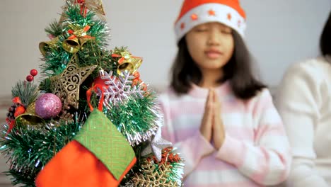 Kleine-Asiatin-einen-Weihnachtsbaum-zu-schmücken-und-beten-für-beste