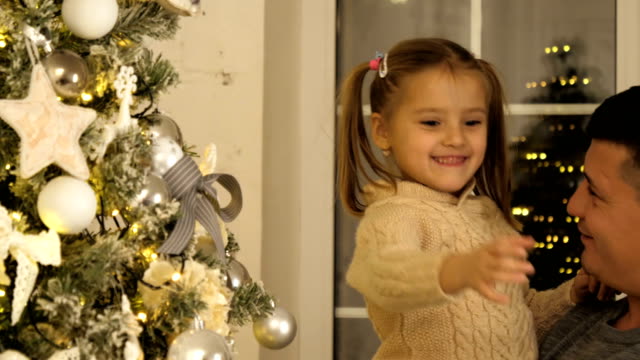Feliz-padre-y-su-pequeña-hija-decorando-el-árbol-de-Navidad-en-casa