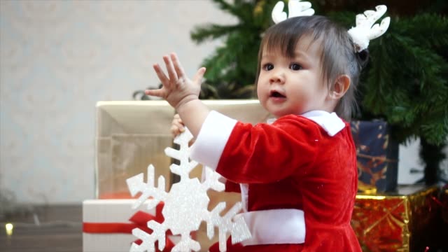 Lindo-1-año-de-edad-niña-con-diadema-de-Reno-jugando-con-adornos-de-Navidad-con-árbol-de-Navidad-de-fondo.-¡Feliz-Navidad-y-felices-fiestas!
