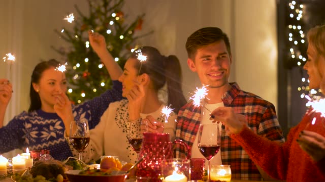 amigos-felizes-Navidad-cenando-en-casa-las-luces-de-Bengala