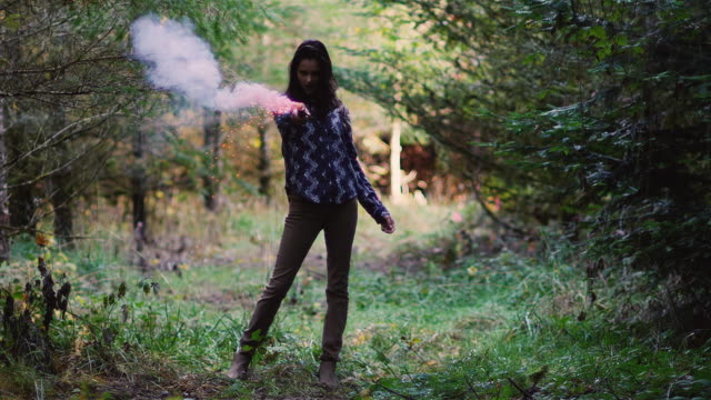 Beautiful-girl-in-a-forest-pulls-a-pink-smoke-grenade-and-waves-it-around,-slow-motion