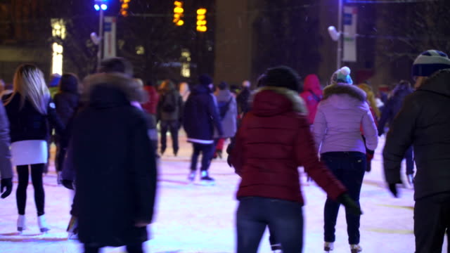 Concepto-de-invierno-y-la-nieve.-Multitud-en-la-pista-de-patinaje-de-la-ciudad-de-la-noche.-Nieve-que-cae.